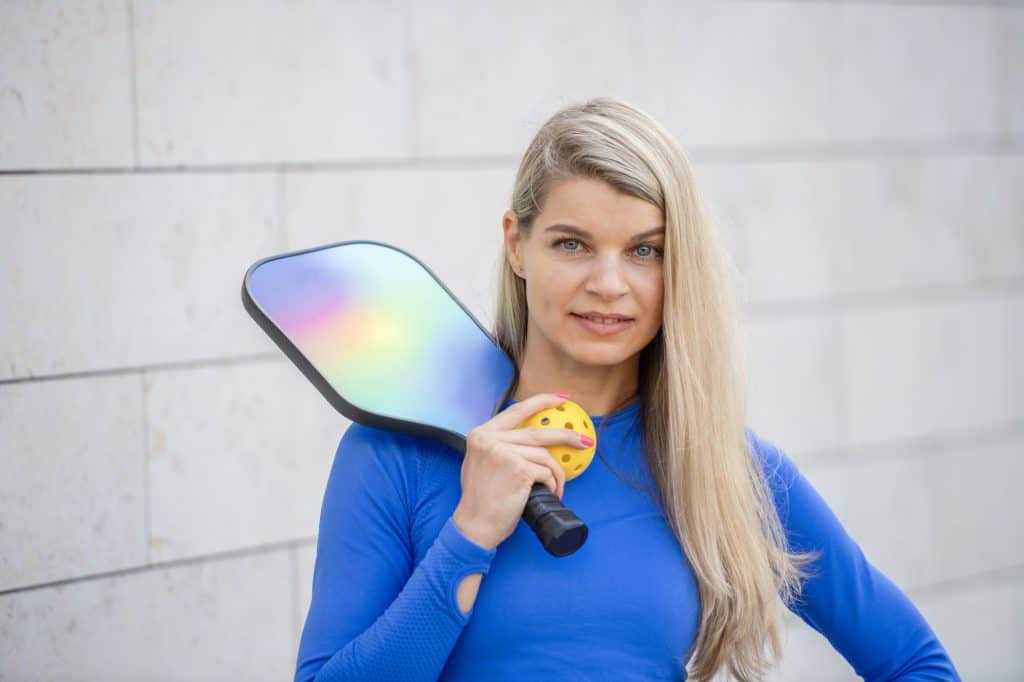 Woman holding a pickleball paddle and ball