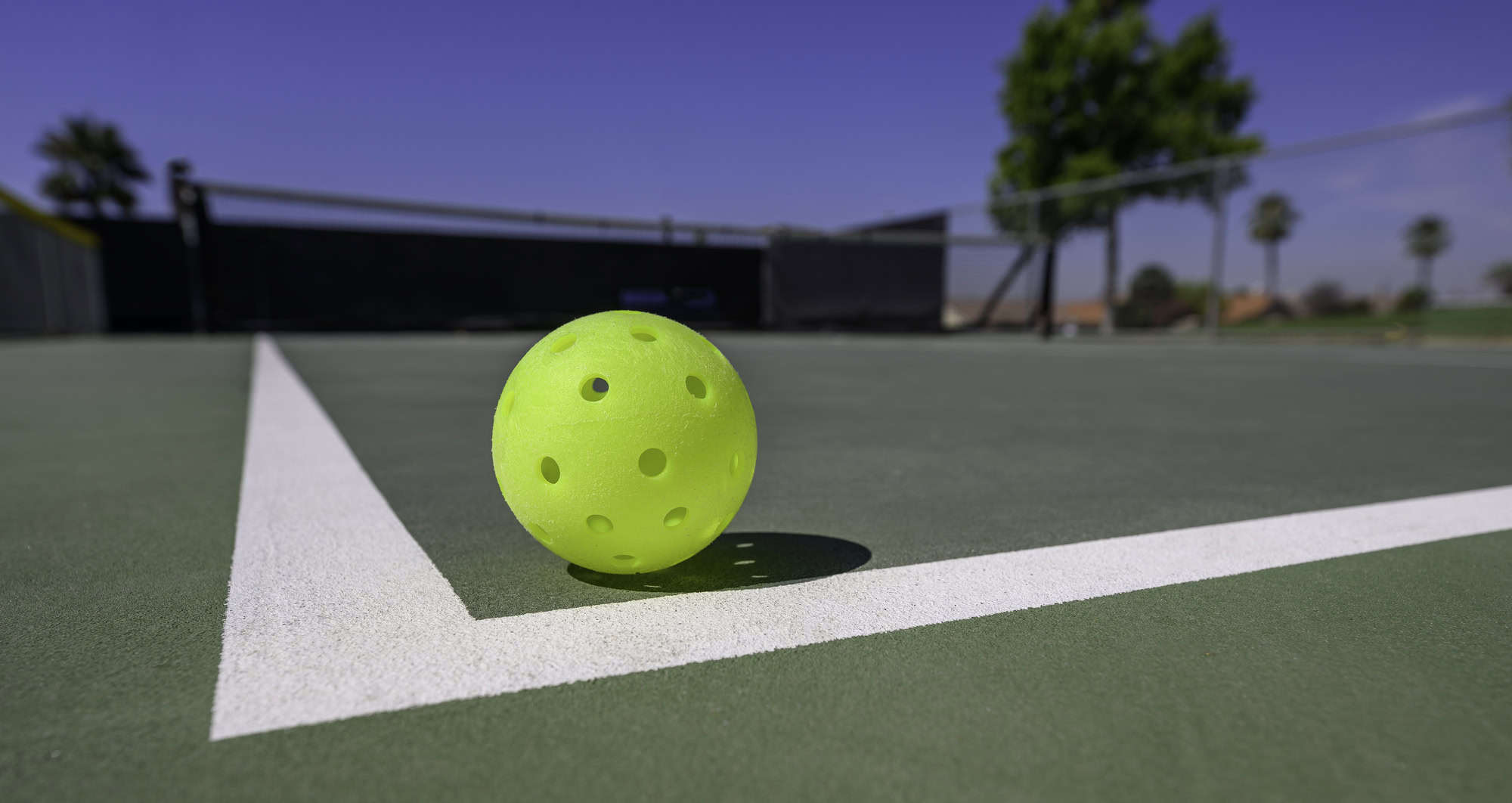 Close-up of a pickleball court with a yellow pickleball on the ground.