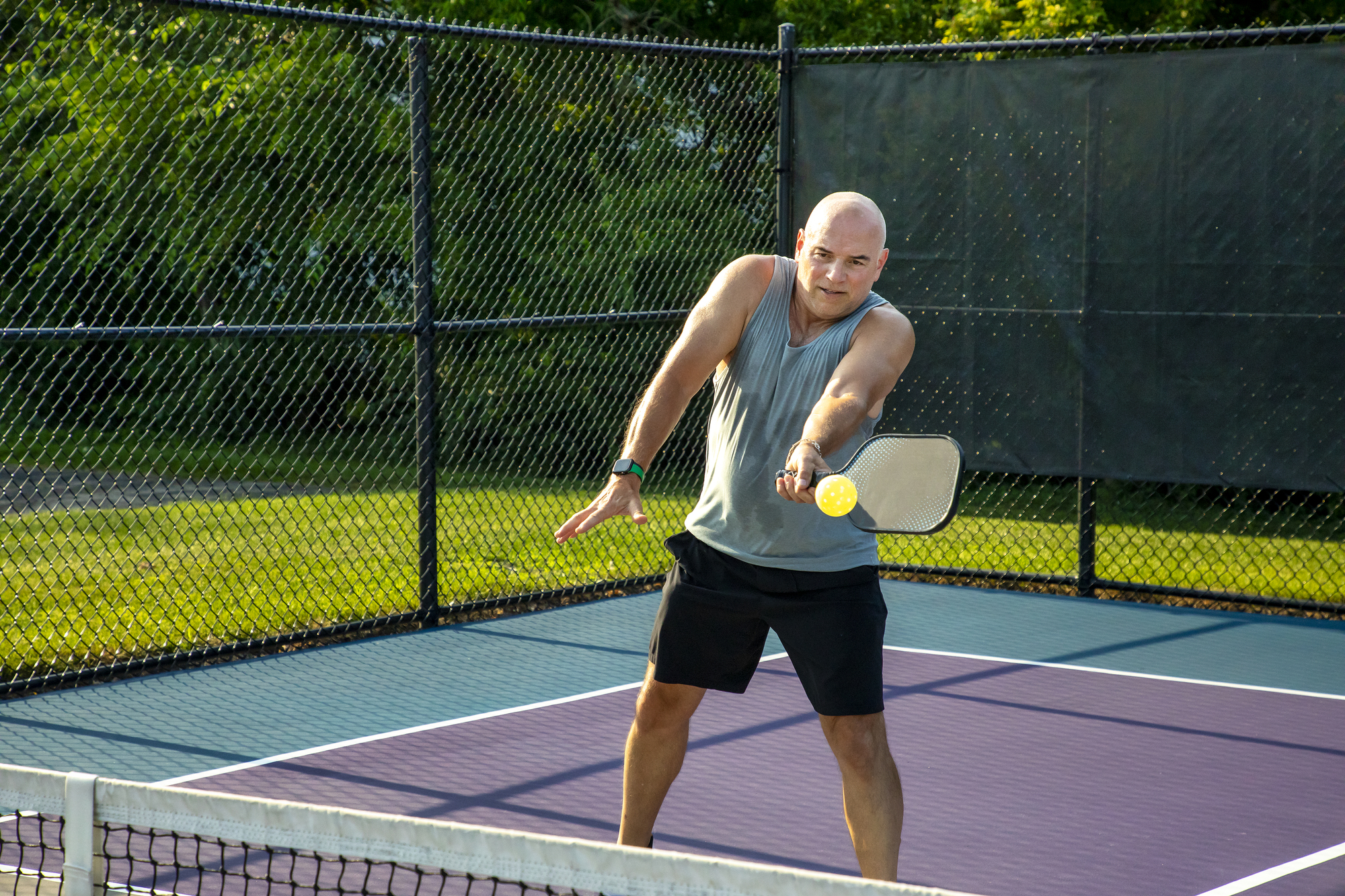 Man hitting a pickleball with a paddle during a game